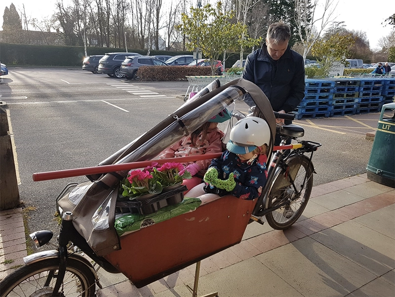 Cargo bike with two small children, bag of compost, and plants